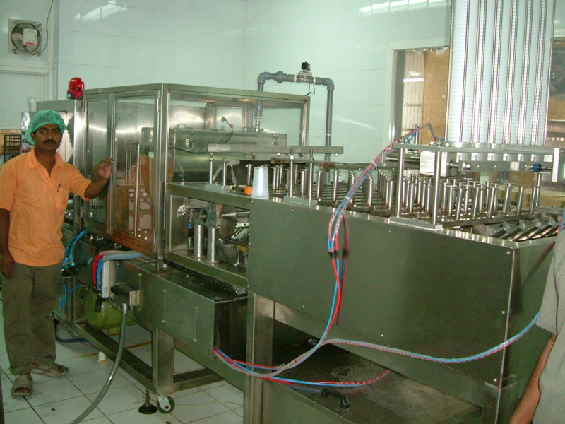 Operator standing beside an EDELSTEIN multi-lane cup filling machine