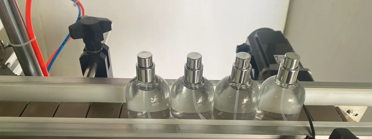 EDELSTEIN cosmetic pump-spray bottles on a filling line conveyor